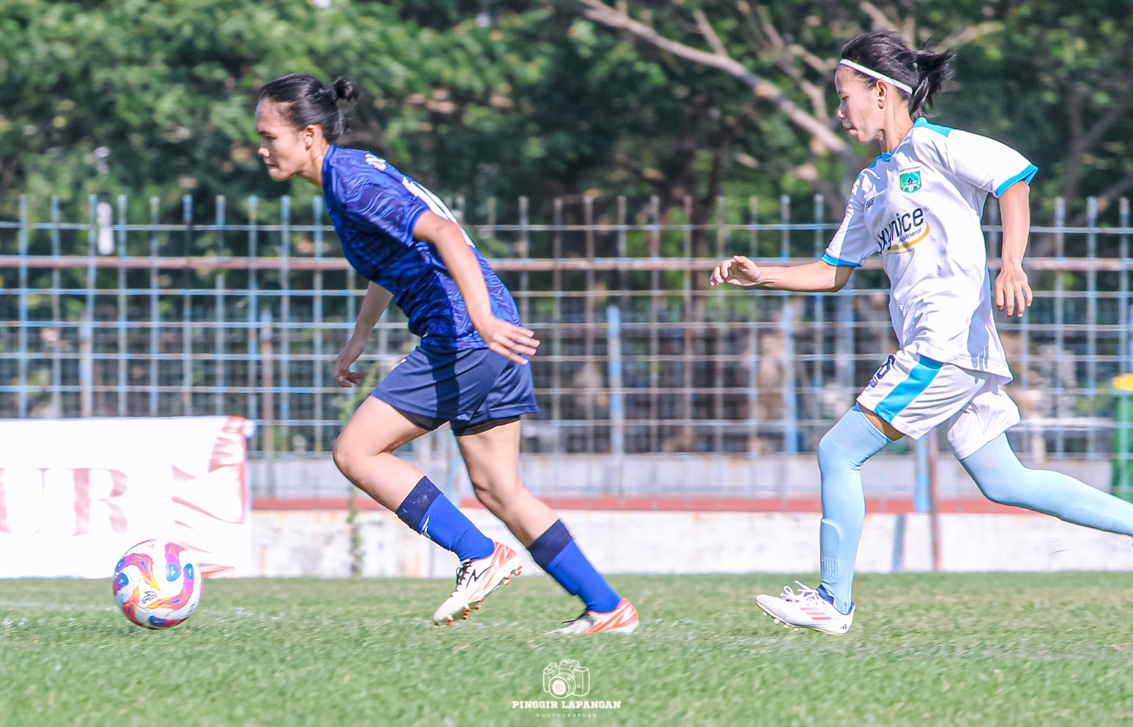 Penyerang Persida Putri Leyli melewati pemain Persikoba Putri di Babak Penyisihan Grup B Piala Kartini 2025 di Lapangan Unesa, Surabaya. Jumat siang (17/10/2025), Persida Putri tampil di semifinal melawan Arek Simo Gresia FC di Jember.